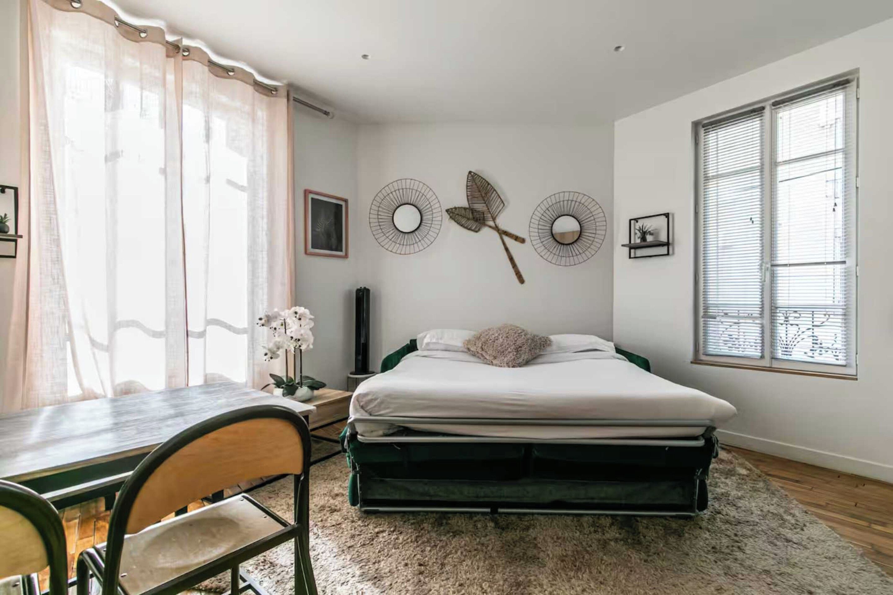 Un dormitorio con una cama, un escritorio y una silla. Hay decoraciones en la pared y una ventana con persianas.