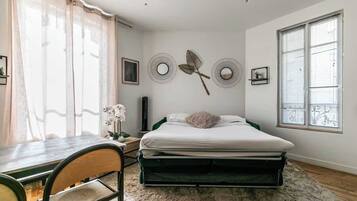 Un dormitorio con una cama, un escritorio y una silla. Hay decoraciones en la pared y una ventana con persianas.