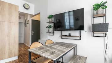 Un espacio habitable moderno con comedor, televisor de pantalla plana montado en la pared y piso de madera.