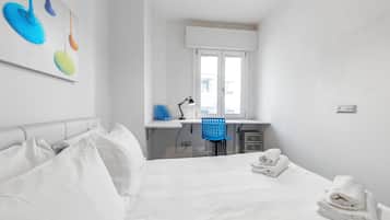 Una camera d'albergo con un letto, una scrivania, una sedia e una finestra.