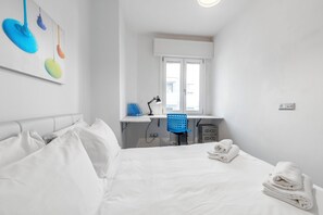 Una camera d'albergo con un letto, una scrivania, una sedia e una finestra.