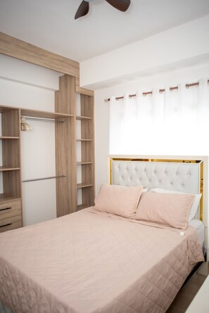 Un dormitorio con cama, armario y ventilador de techo.