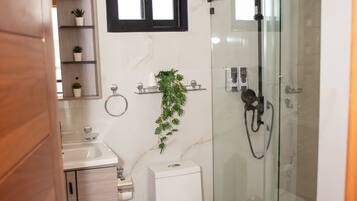 Une salle de bain moderne équipée de toilettes, d’un lavabo et d’une douche à parois de verre.