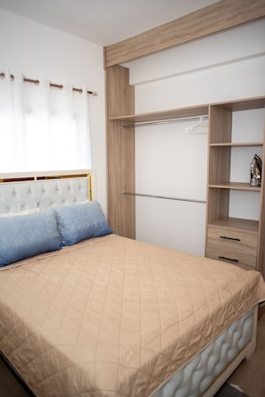A bedroom with a bed, a wardrobe, and a window with curtains.