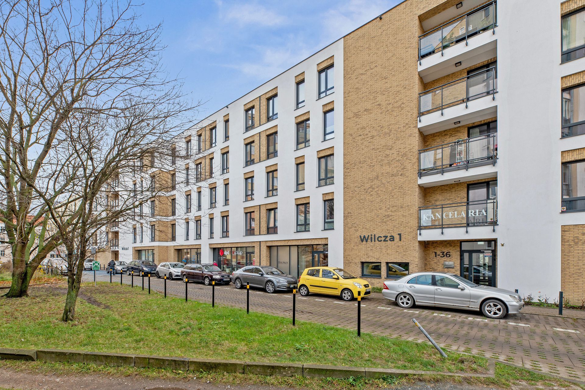 Een meerlaags woongebouw met een modern ontwerp, bestaande uit baksteen en witte gevels, en een zichtbare ingang met een bord.