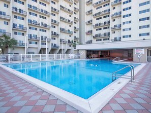 A swimming pool with a tiled deck, surrounded by a white fence, and adjacent to a multi-story building with balconies. - Pinnacle Port Penthouse A-PH10 - Margery's Retreat (Panama City Beach)