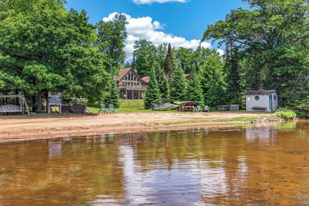 Une propriété au bord du lac comprenant une grande maison, un chalet plus petit et un quai.