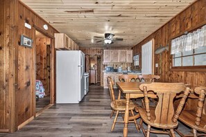A wooden interior with a dining table and chairs, a refrigerator, and a ceiling fan. - Stepaway Vacation Rentals/Hillcrest Cottages-Maple (St.Germain)