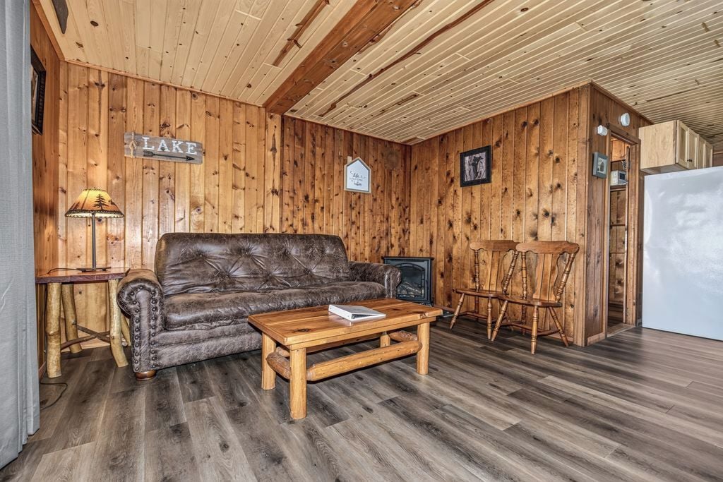 A wooden interior with a leather sofa, a wooden coffee table, and a fireplace.