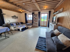 Ein gemütliches Wohnzimmer mit einer Couch, einem Couchtisch, einem Bücherregal und einem Fernseher.