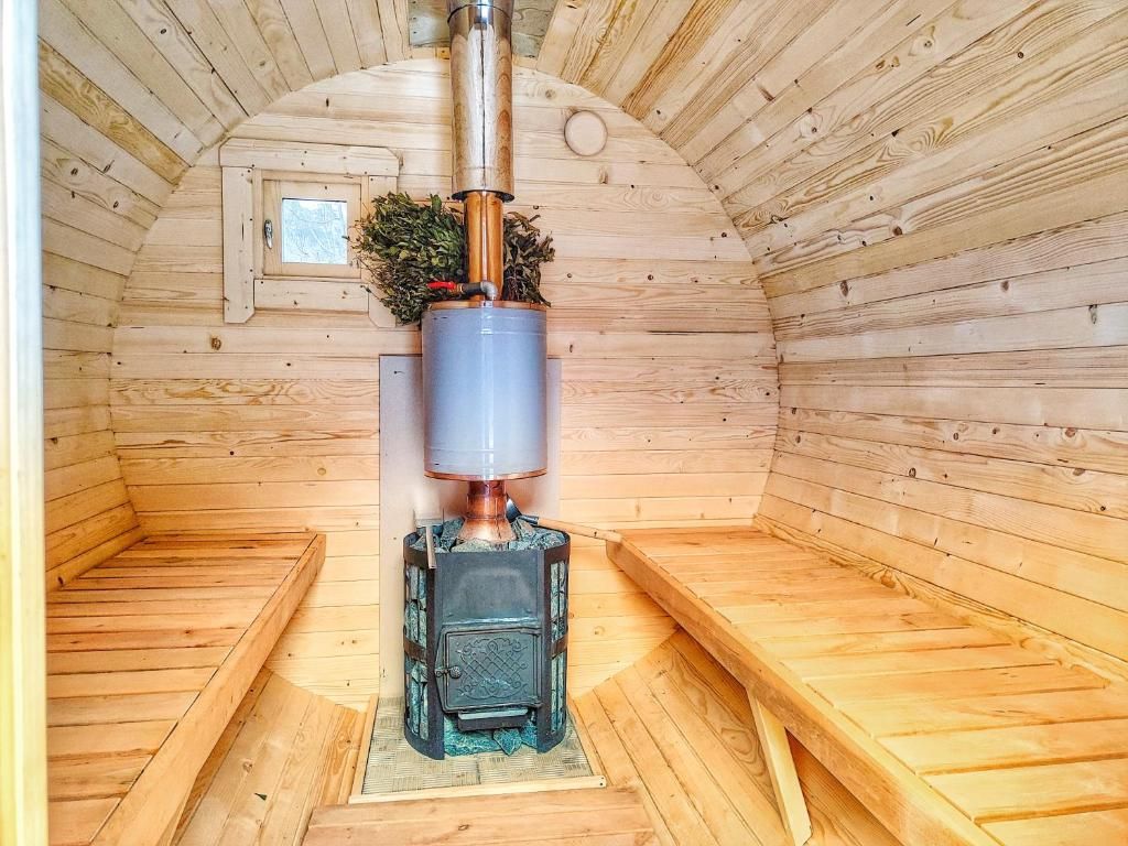 Un sauna avec des murs et des bancs en bois, un système de chauffage central et une petite fenêtre.