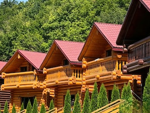 A row of log cabins with balconies, surrounded by evergreen trees. - Sonat Resort (Gosh)