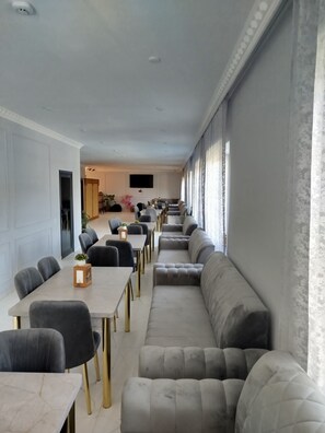 A modern dining area with a long table and multiple seating options, including a sofa and chairs.