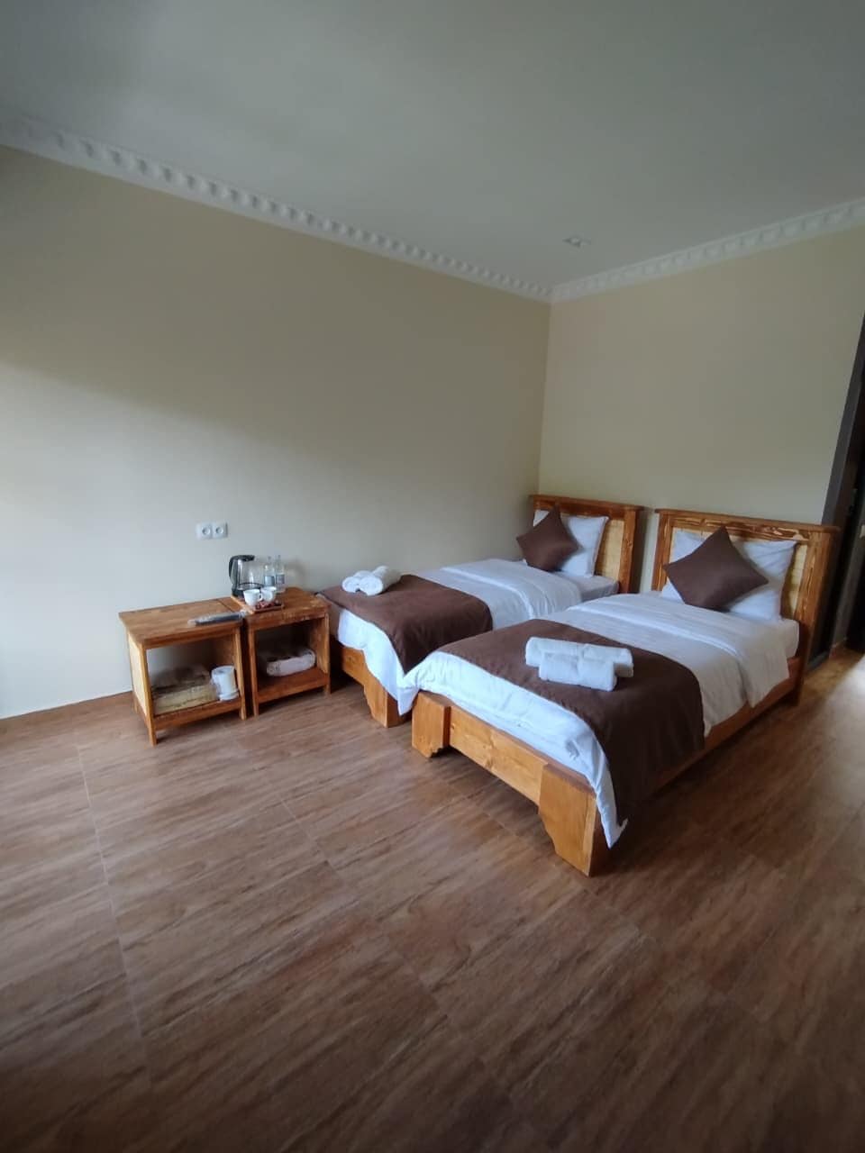 A hotel room with two beds, a wooden nightstand, and a small table.