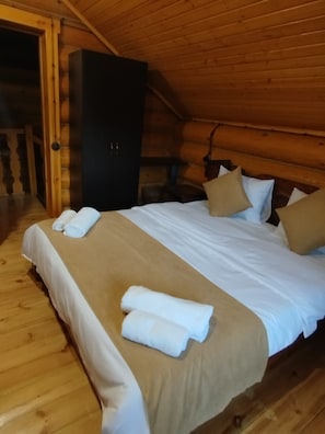 A wooden cabin room with a bed, pillows, and a wardrobe.