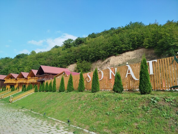 A wooden fence with the word 'SONATA' and a row of log cabins with red roofs.