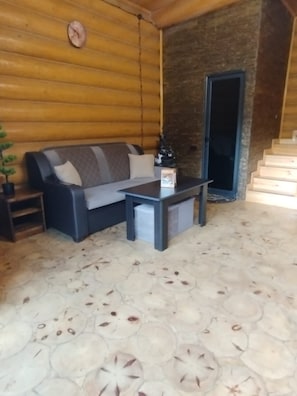 A log cabin interior with a sofa, coffee table, and a small plant.