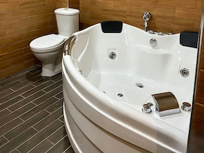 A bathroom with a white bathtub, a toilet, and a wooden wall. - Sonat Resort (Gosh)