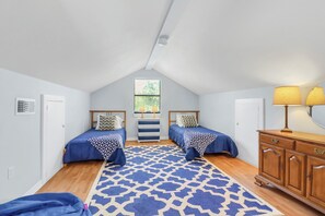 A bedroom with two beds, a patterned rug, a wooden dresser, and a window with blinds. - Hidden Creek Hideaway | Hot Tub, 2 Acres & Near Jacob's Well (Wimberley)