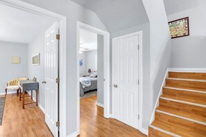 Ein Flur mit einer Treppe, die zu einem Schlafzimmer mit einem Bett und einem Nachttisch führt.