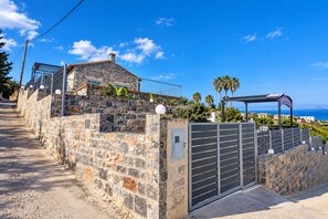 Ein Gebäude mit Steinmauern, einem Metallgitter, einem überdachten Außenbereich und Blick auf das Meer.