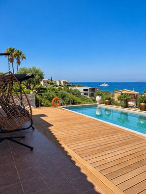 A poolside area with a swing chair, a lifebuoy, and a view of the sea. - Amberstone Traditional Villa with Sea View,Private pool and 3 Bedrooms (Vathianos Kampos)