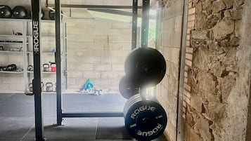 A weightlifting area with a squat rack, barbells, and weight plates.