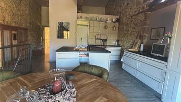 A modern kitchen with white cabinets, a wooden dining table, and a herringbone floor pattern.