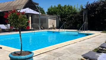 Ein Schwimmbecken mit Liegestühlen und einem Topf mit Pflanze.
