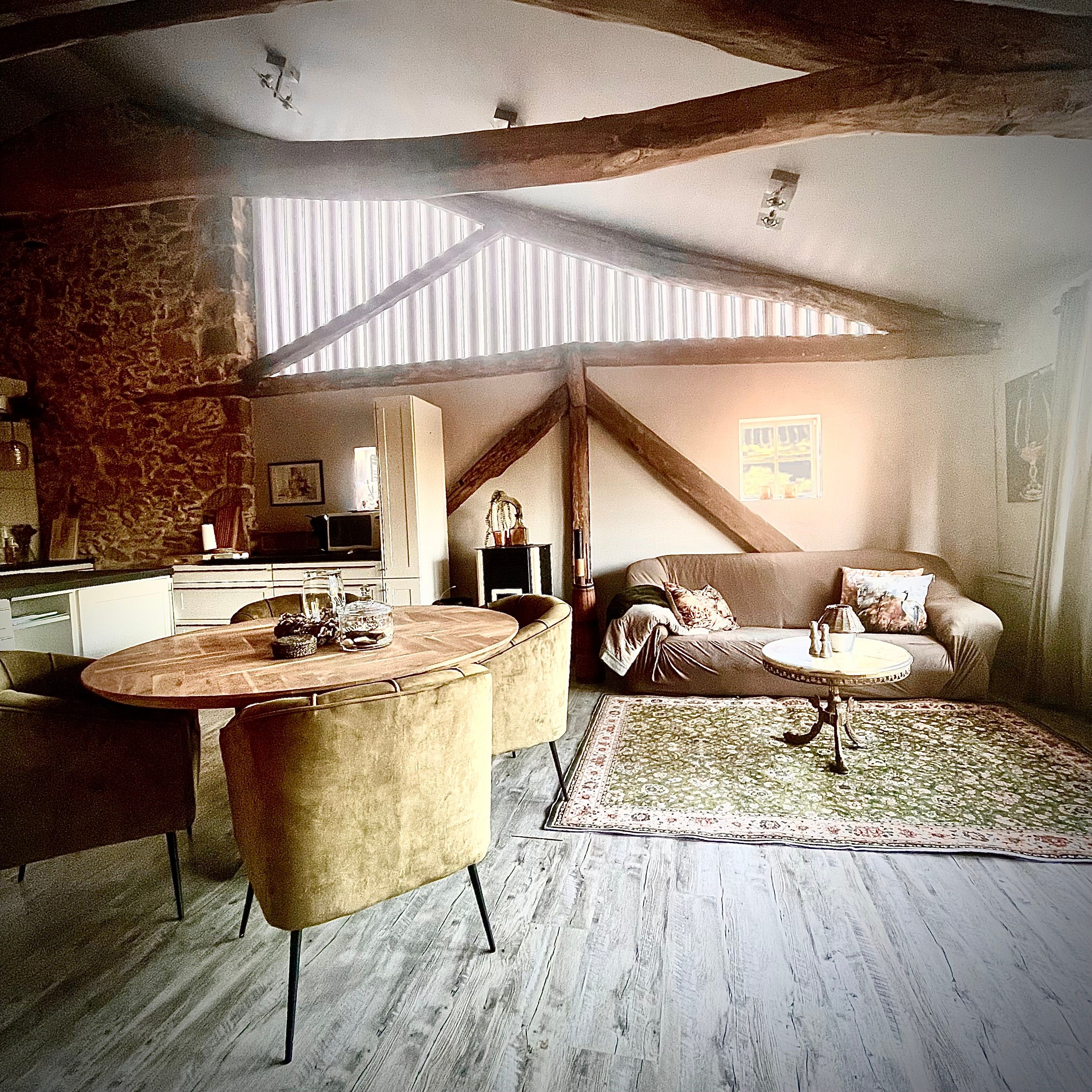 Um quarto acolhedor no estilo loft, com área de jantar, sofá e cozinha ao fundo.