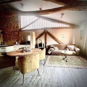Un acogedor espacio tipo loft con comedor, un sofá y una cocina al fondo.