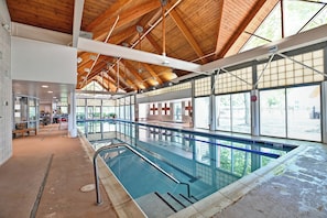 Una piscina coberta amb un sostre alt i grans finestres.