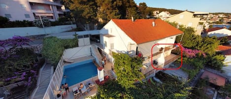 A residential property with a swimming pool, a covered patio, and a view of neighboring buildings.