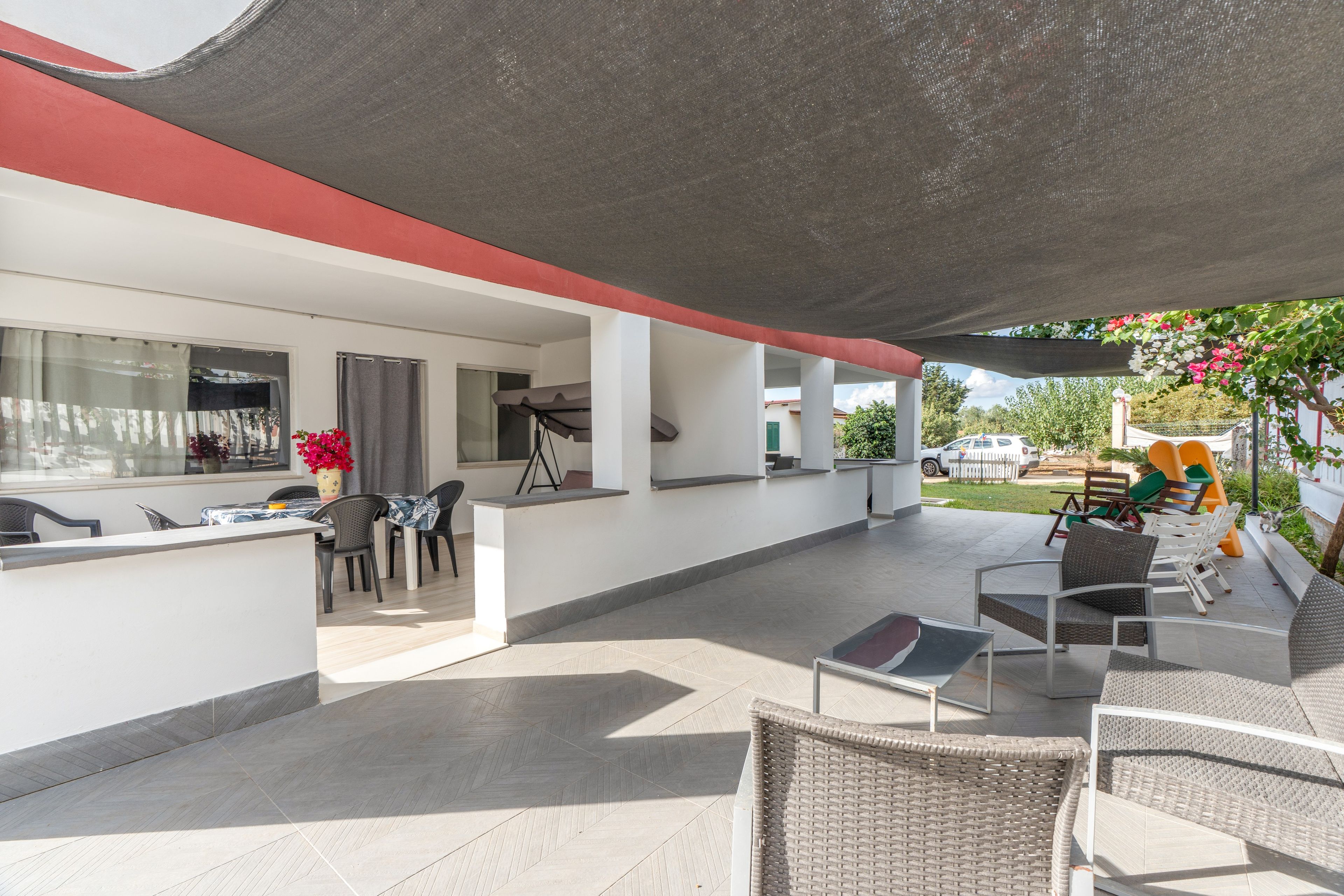 An outdoor patio area with a dining table, chairs, and a seating area with a table and chairs.