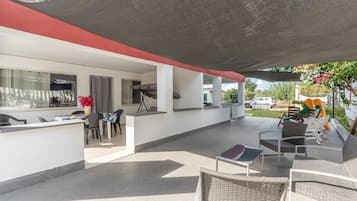 An outdoor patio area with a dining table, chairs, and a seating area with a table and chairs.