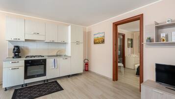 A compact kitchen with modern appliances, a small dining area, and a TV.