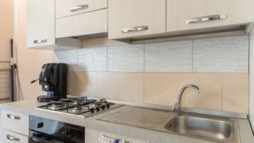Eine moderne Küche mit Edelstahlgeräten, einem Gasherd, einem Backofen und einer Spüle.