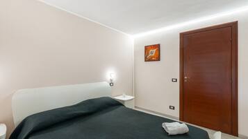 A bedroom with a bed, bedside table, wall art, and a door.