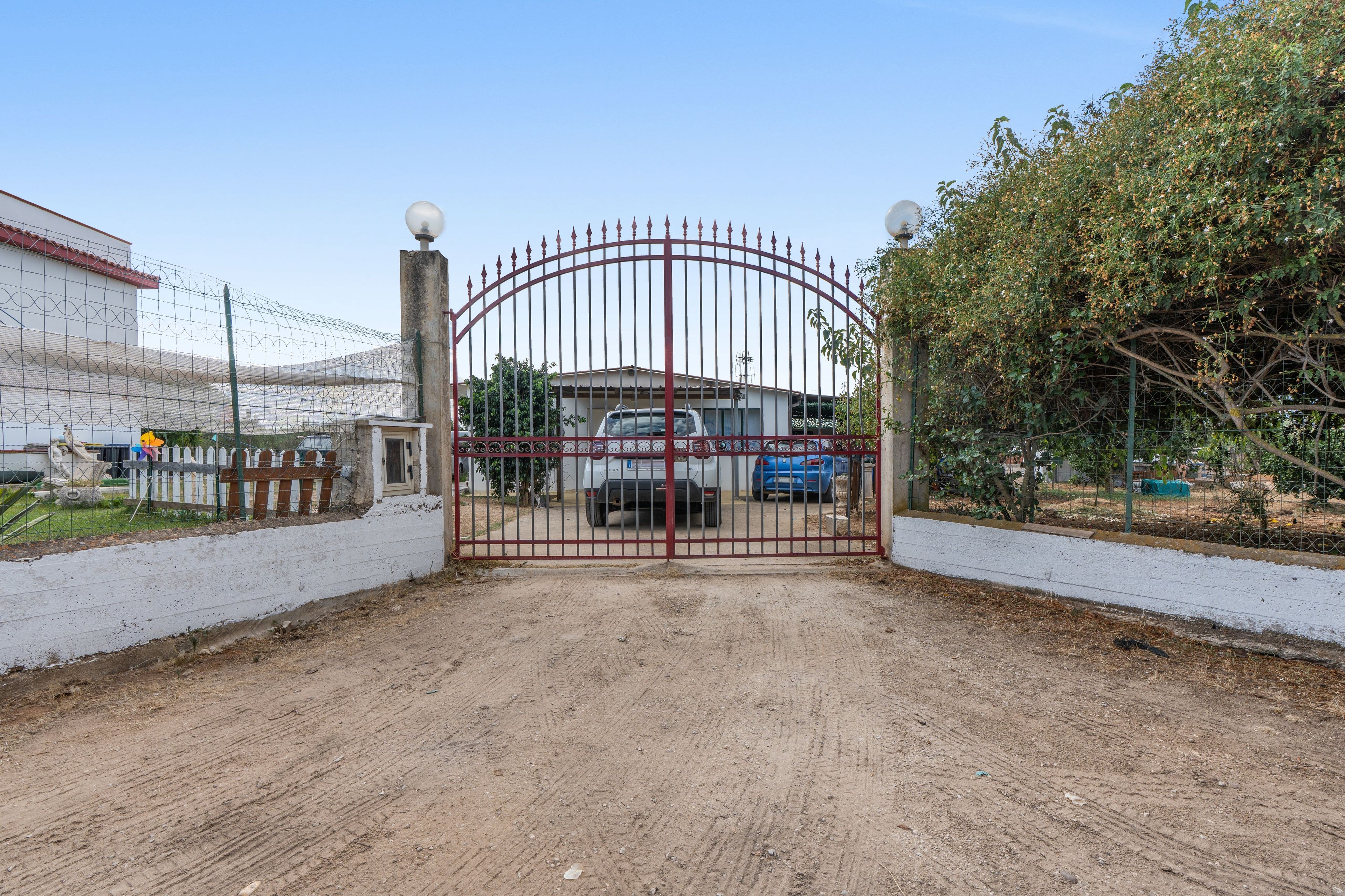 A gated entrance with a dirt path leading to a building.