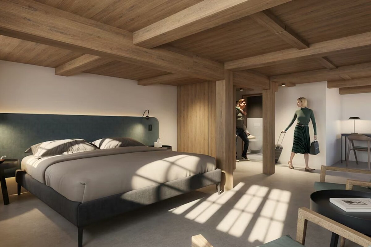 A modern bedroom with a large bed, a desk, and a chair.