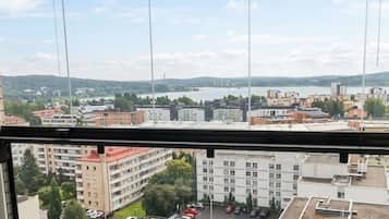 Näkymä ikkunasta, josta avautuu näkymä parkkipaikalle, jossa on rakennuksia ja kauempana horisontissa maisema.