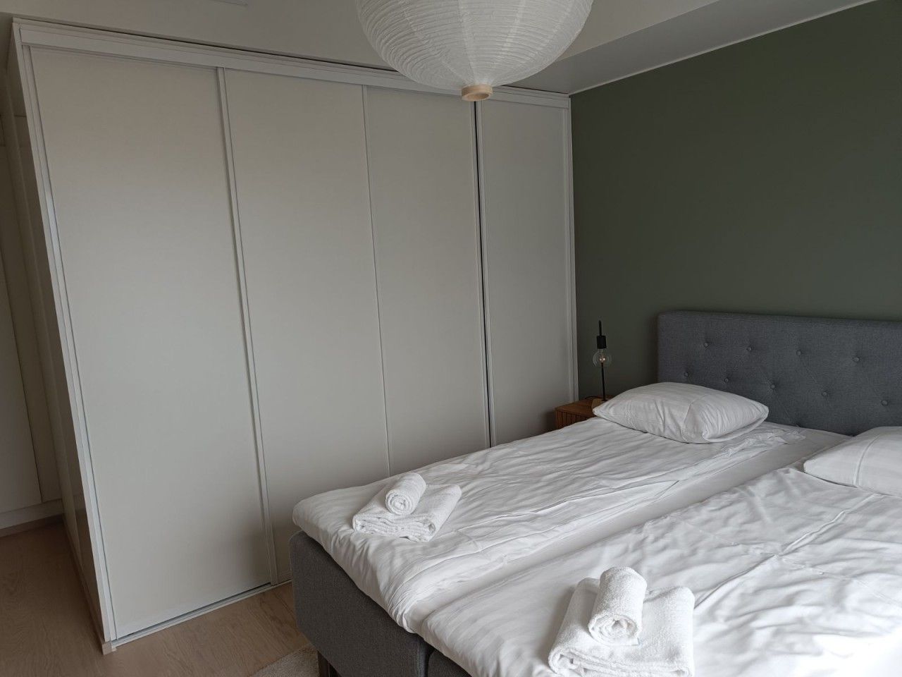 Un dormitorio con cama, almohadas, mesita de noche y armario.