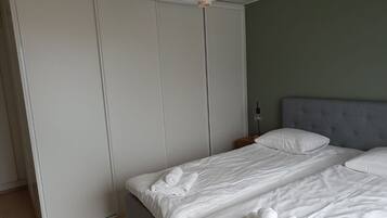 Un dormitorio con cama, almohadas, mesita de noche y armario.