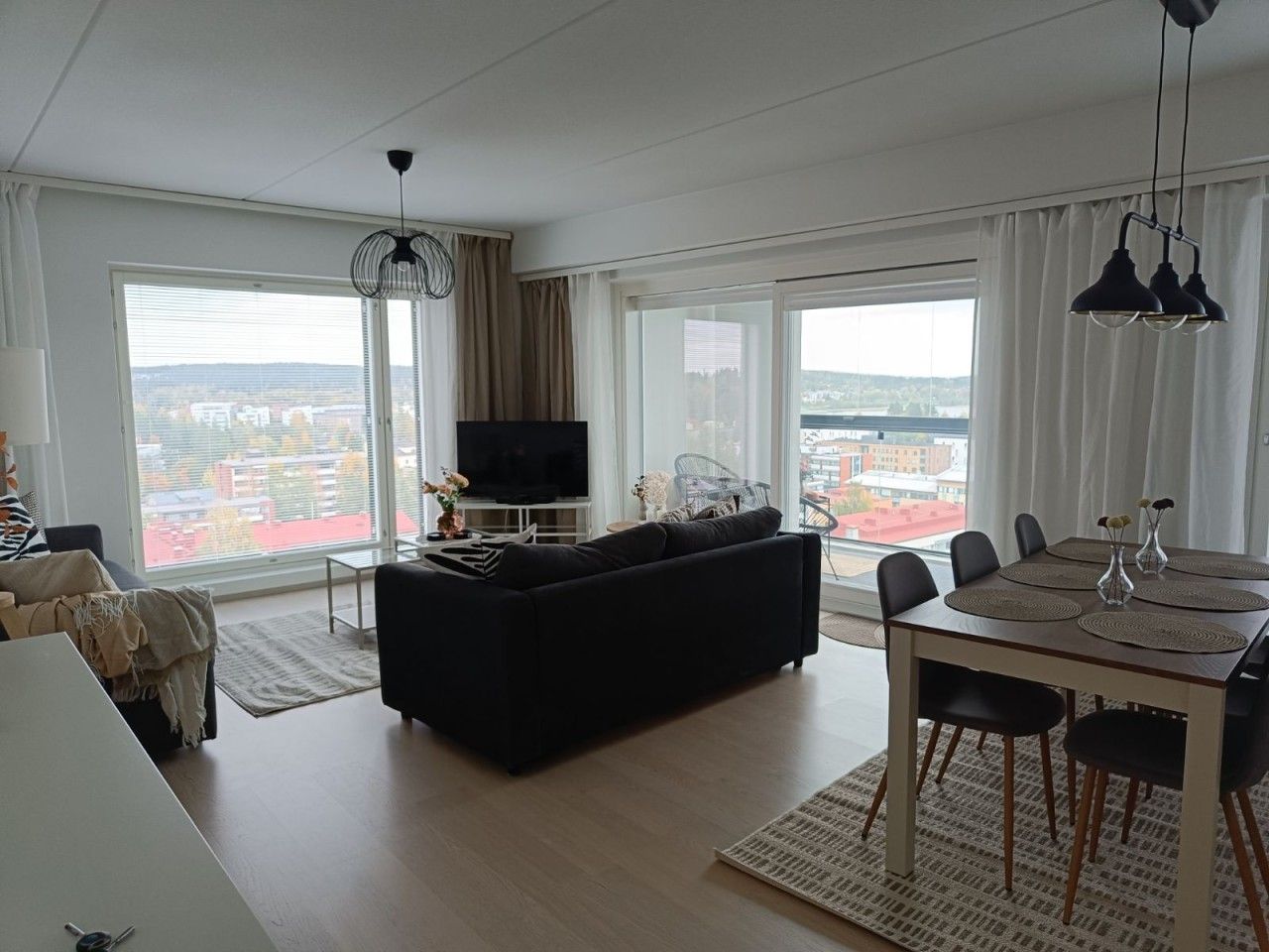 Una sala moderna con sofá, televisor, mesa de comedor y sillas.