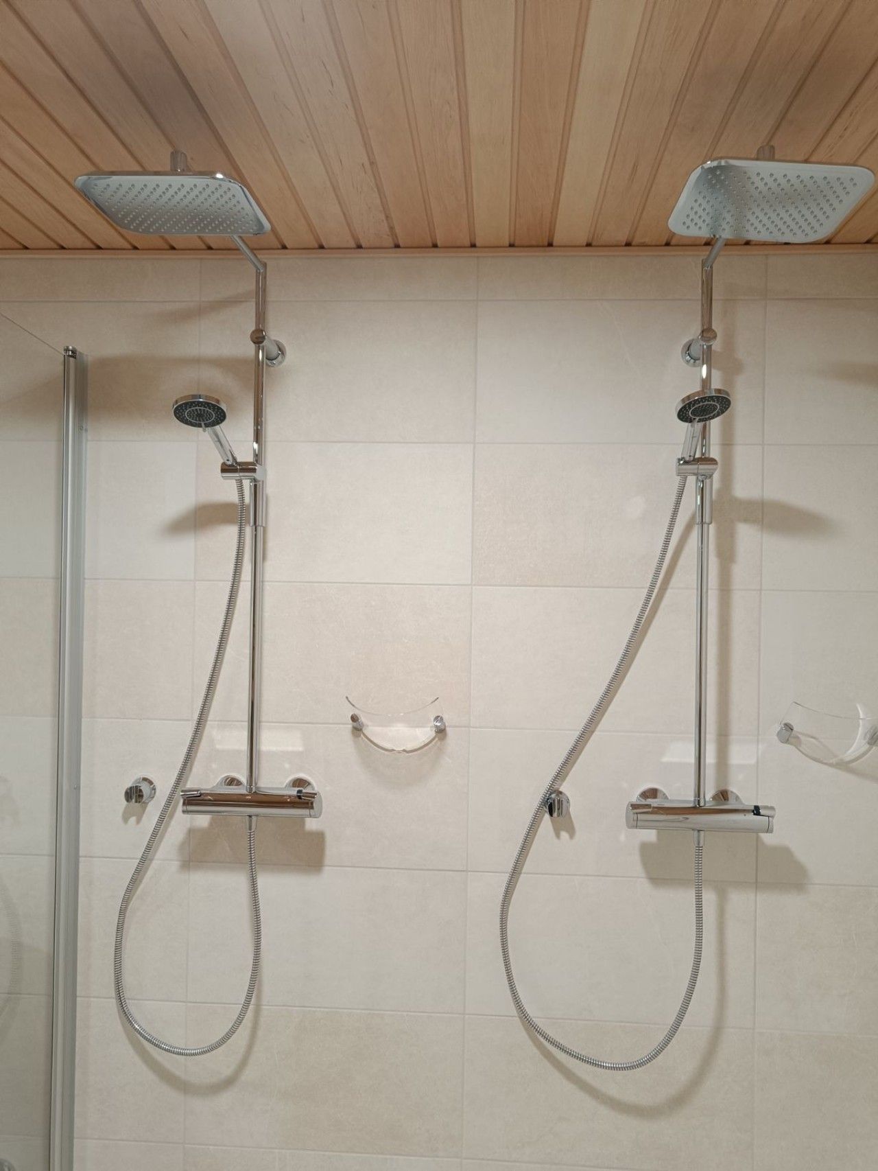 A shower area with two showerheads and a glass enclosure.