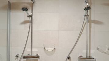 A shower area with two showerheads and a glass enclosure.