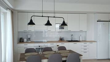 Una cocina moderna con armarios blancos, una isla central con taburetes e iluminación colgante.
