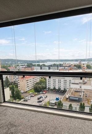 Vista desde una ventana sobre un estacionamiento, con edificios y un cuerpo de agua a lo lejos.