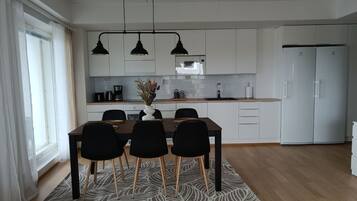 Une cuisine moderne avec des meubles blancs, une table à manger avec des chaises et un réfrigérateur.