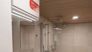 Moderni kylpyhuone, jossa on valkoinen allaskaappi, peili, wc ja lasiseinällä erotettu suihkutila.
